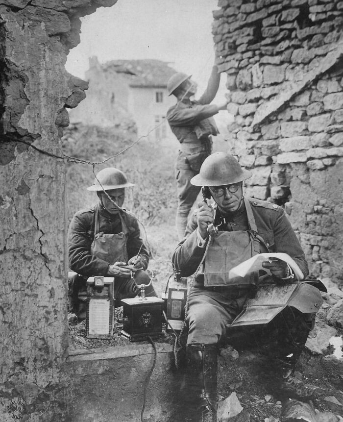 Lieutenant Colonel R. D. Garrett of the 42nd Division tests a telephone left behind by retreating German troops in Essy, France, 1918.