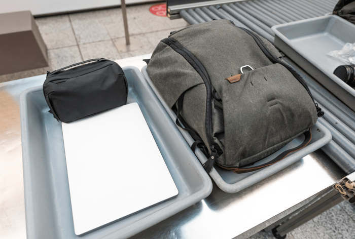 Airport security screening bins with personal items on a conveyor belt.