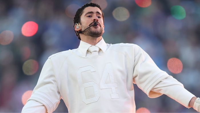 Bad Bunny stands on halftime stage with star-studded surprise entrance crowd.