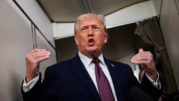 Donald Trump at a podium, referencing Greenland control and international backlash.
