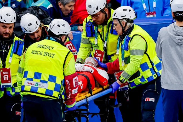 Olympic short-track speed skater on ice, medical team responding after face injury