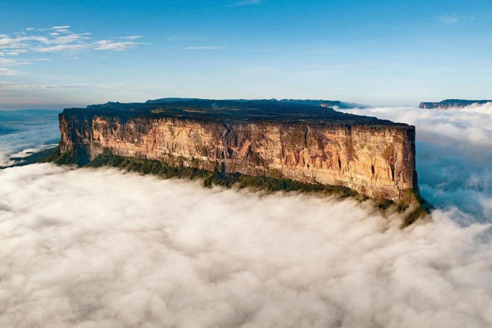 Hikers approaching Mount Roraima summit in rugged rainforest, emphasizing isolation and difficulty.