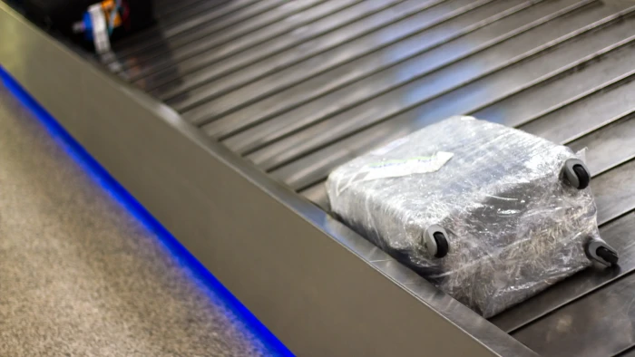 Close-up of suitcase wrapped in plastic, warning about increased security risks