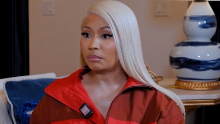 Nicki Minaj at summit, posing near Trump-related gold card visa symbol.
