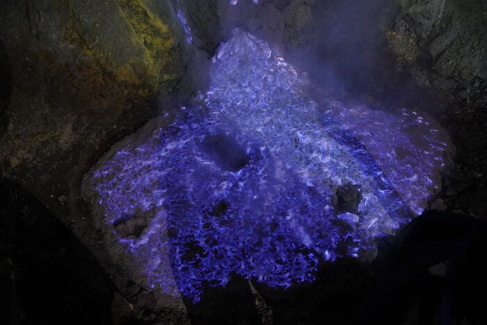 Kawah Ijen in Indonesia is a volcanic crater where sulfuric gases combust into bright blue flames after dark—a geological phenomenon so visually alien it looks like the planet is running unofficial software.