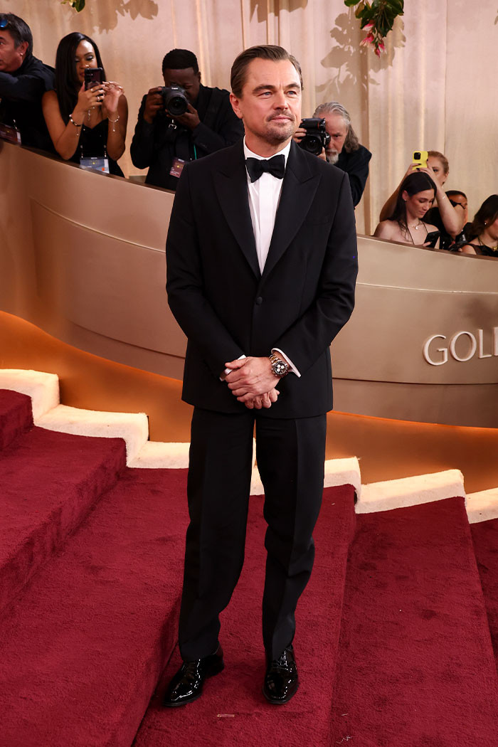Leonardo DiCaprio wore a sleek black-and-white Dior tuxedo with satin lapels, styled with a white dress shirt, black bow tie, and polished Manolo Blahnik lace-up leather shoes.