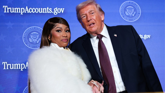 Nicki Minaj stands beside a Trump “Gold Card” amid political controversy.
