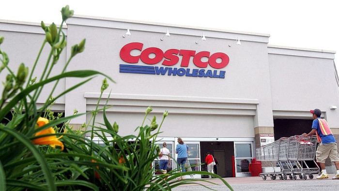 Shopper comparing food labels on Costco rotisserie chicken, focusing on transparency issues