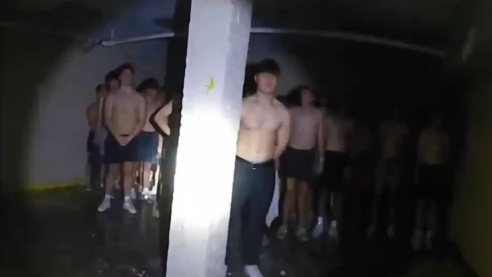 Shirtless, blindfolded men, covered in mysterious substances, shown in fraternity bodycam footage