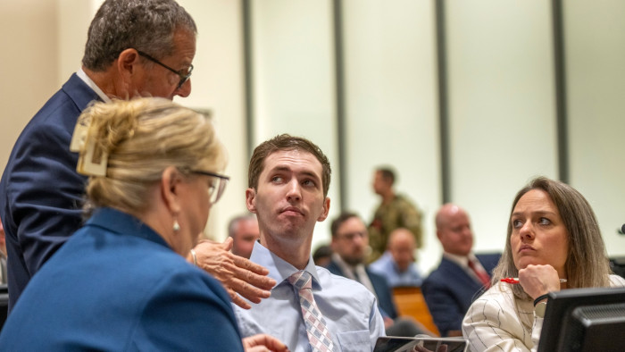 Attorneys and court officials seated in a courtroom during a hearing preparation.