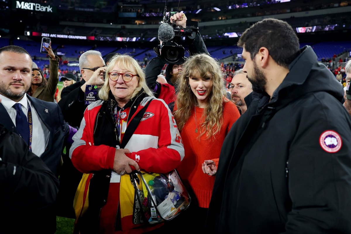 Taylor Swift is seen here standing on the field in the middle of a crowd with Travis Kelce's mom.