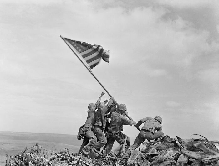 The iconic 1945 scene of the flag being lifted at Iwo Jima stands as a symbol of strength and resolve.