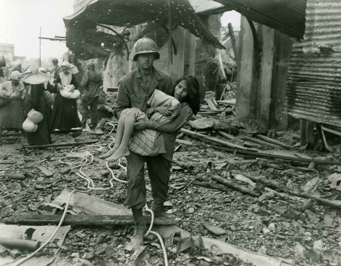 "An American Soldier Carries an Injured Filipina Girl Through the Rubble of Manila, February 23, 1945."