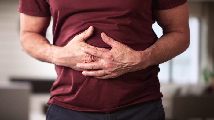 Person holding lower abdomen, signaling fatigue and unexplained weight loss symptoms