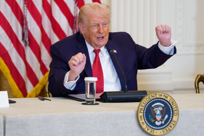 Donald Trump seated at a desk, looking somber amid political turmoil.