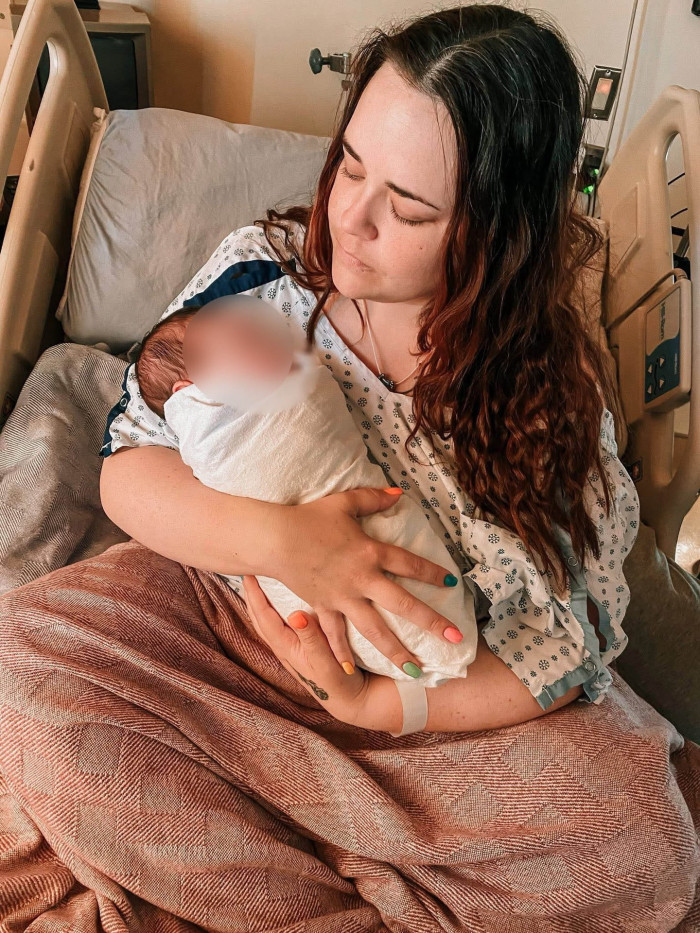 Surrogate mother holding a baby blanket, reflecting on complex emotions