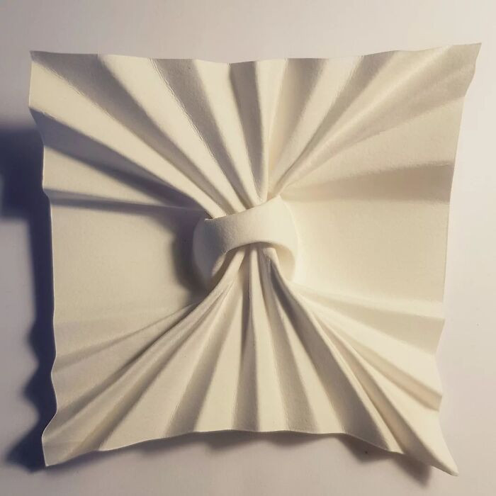 Origami paper portrait with vaulted ceiling folds, rhomboid twist corrugation texture detail.