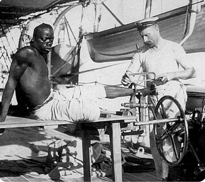 A British blacksmith aboard HMS Sphinx removes leg irons from an enslaved person in 1907.