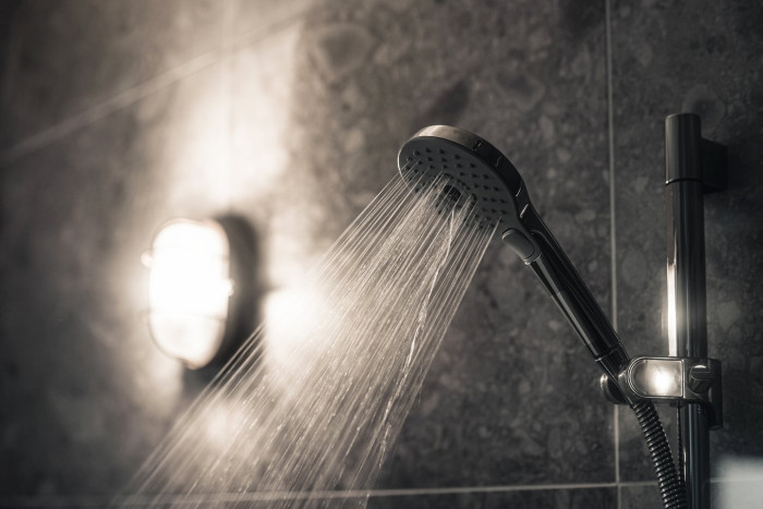 Person showering under dim, dark lighting to support better sleep quality