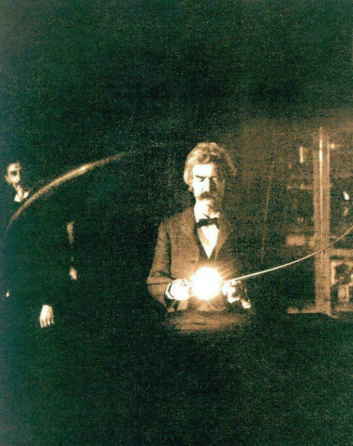 "Mark Twain Holding A Lamp Lit Without A Wired Connection In Nikola Tesla's Laboratory While Tesla Watches From The Shadows, 1894"