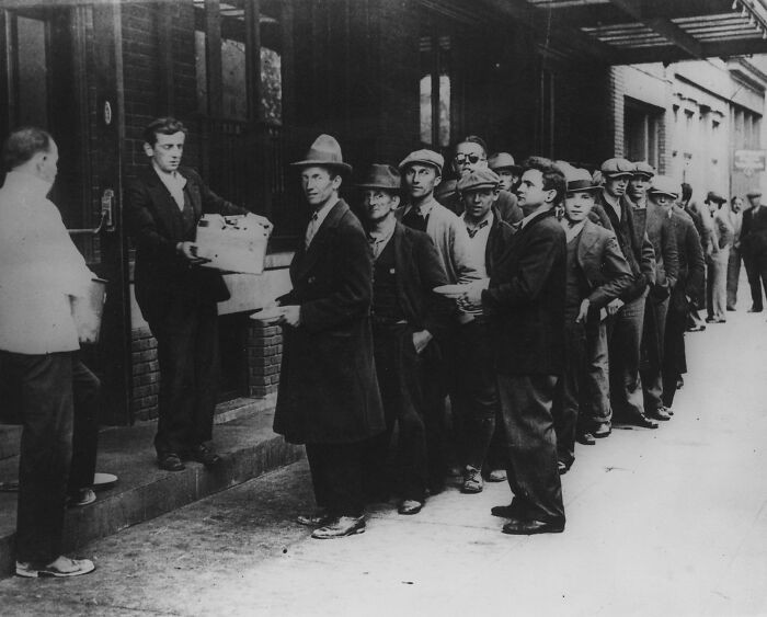 A long line of unemployed people waits for a meal during the Great Depression. In 1932, New York City saw many rely on privately funded food programs that stepped in to provide free meals to struggling residents across urban neighborhoods.