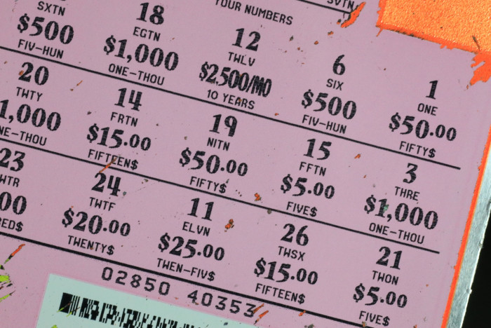 Woman smiling beside lottery tickets, celebrating four big winning jackpots