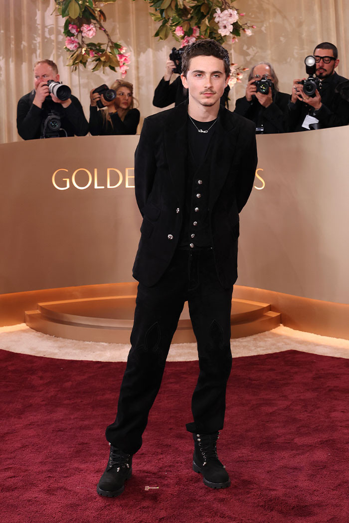 Timothée Chalamet opted for a sharp black suede suit paired with a clean white shirt, finishing the look with black Timberland boots and a subtle necklace.