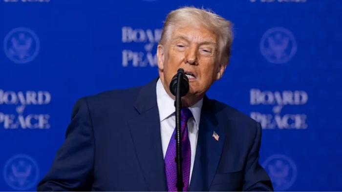 Donald Trump speaking at the Board of Peace event, hand gesture
