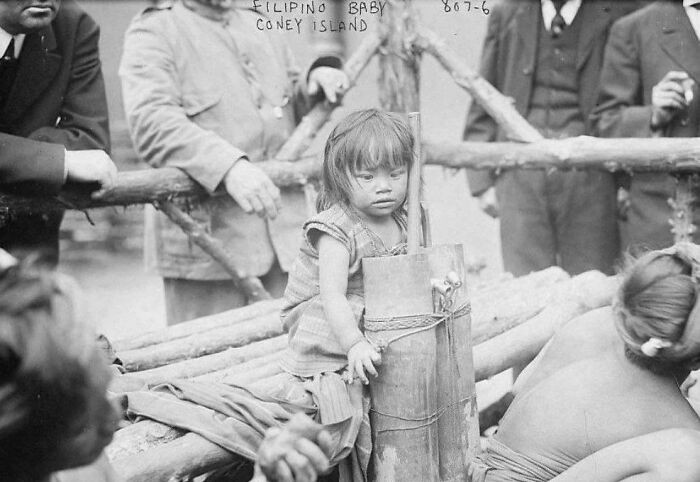 This 1905 image captures a disturbing “human zoo” exhibit at Coney Island, where visitors paid to watch a young Filipino girl displayed as an attraction. Tied to a pole and mocked by onlookers, she was treated as entertainment, exposing the racism of the era.