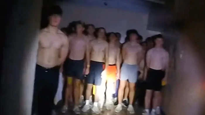 Fraternity hazing controversy, group participants shown in blindfold activity context.