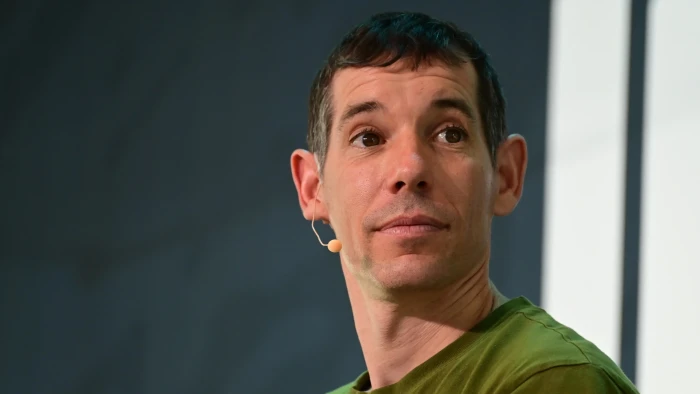 Alex Honnold climbing high on Taipei 101, discussing passion over profit