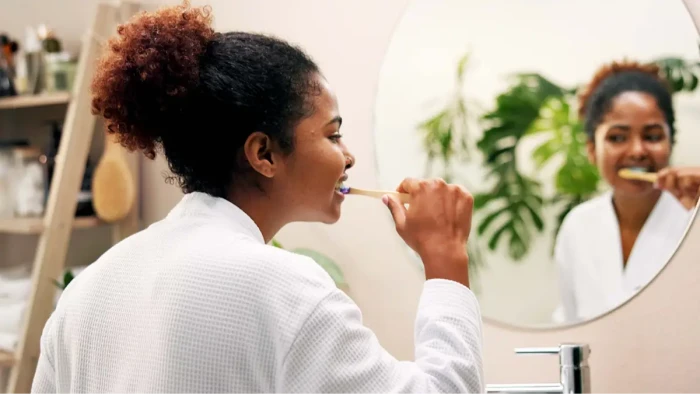 Person brushing teeth and cleaning tongue, promoting three-times-daily oral care