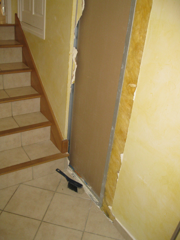 The current opening sits inconveniently in the middle of the hallway, which isn't feasible. Therefore, he began chiseling away at a wall near the stairs leading down to the garage.