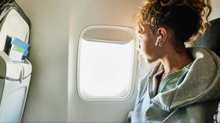 Passenger looks frustrated as cabin sunlight glares through open aircraft window