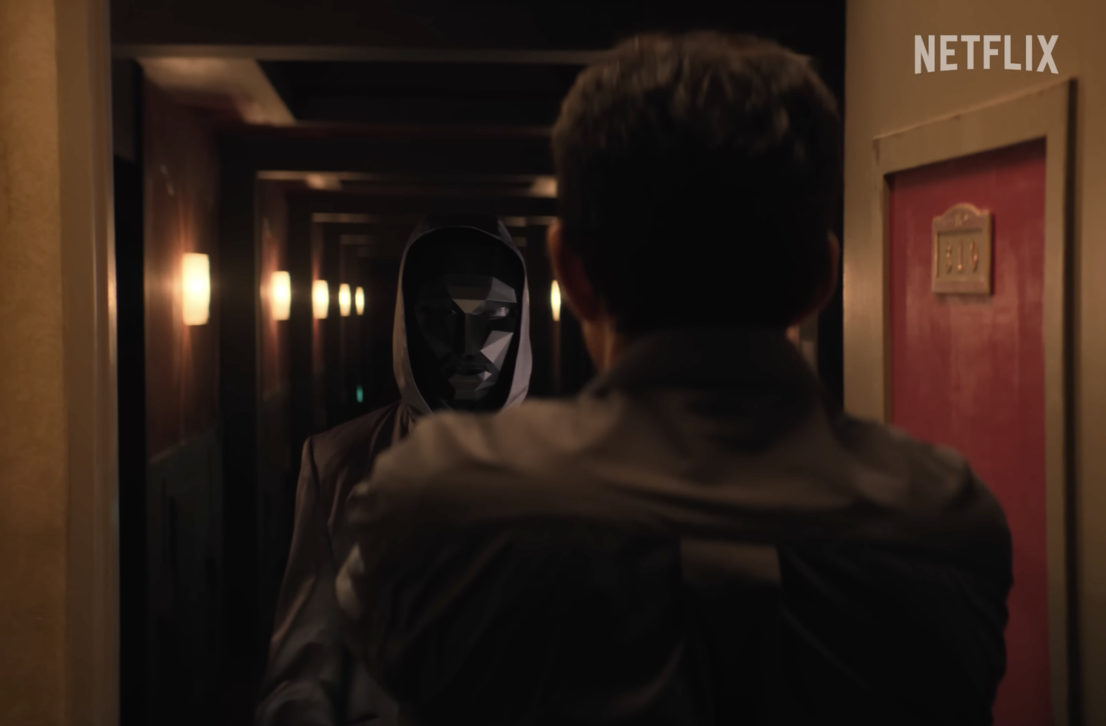 He opens the door holding a gun and is surprised to see the unwelcome sight of the Front Man.