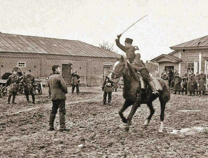 "A Cossack Policeman, to the Amusement of Hungarian Soldiers, Slashes a Captured Soviet Partisan with a Saber, Occupied Ukraine SSR, September 1941."