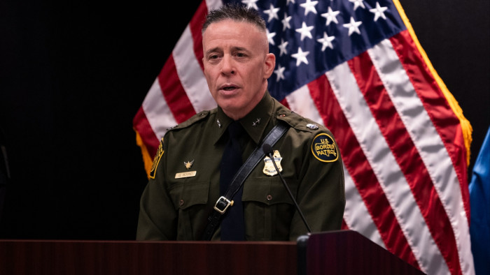 Press scene with border enforcement officials, linked to debate over lethal force.
