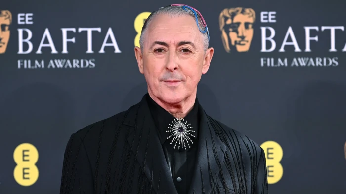 Alan Cumming speaking at an event, addressing controversy over a racial slur