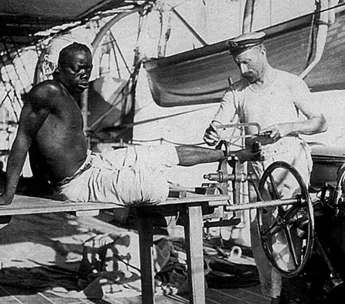 "British Blacksmith Removing The Leg Irons Off A S***e, 1907. "