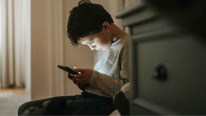 Parent and child reviewing smartphone rules, emphasizing responsible youth screen use