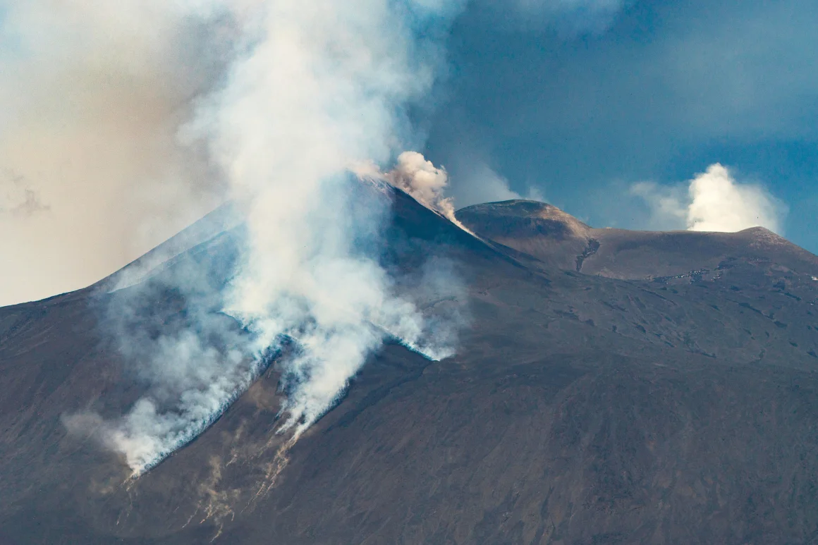 Smoke rises from Mount Etna as tourists rush to escape its latest eruption.