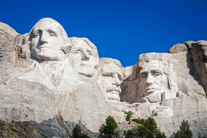 Holiday weekend travelers and shopping sales signage referencing President’s Day origins