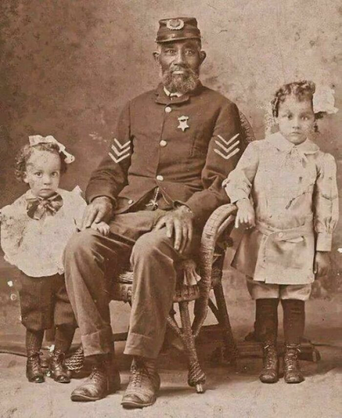 A former Civil War soldier pictured alongside his grandchildren, capturing a quiet moment between generations shaped by history.