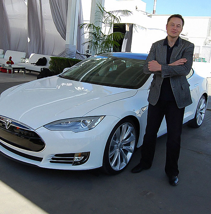 Casually leaning on a Tesla, Musk wonders: What’s more impressive, my car or the fact that I look this good at 5,000 years old?