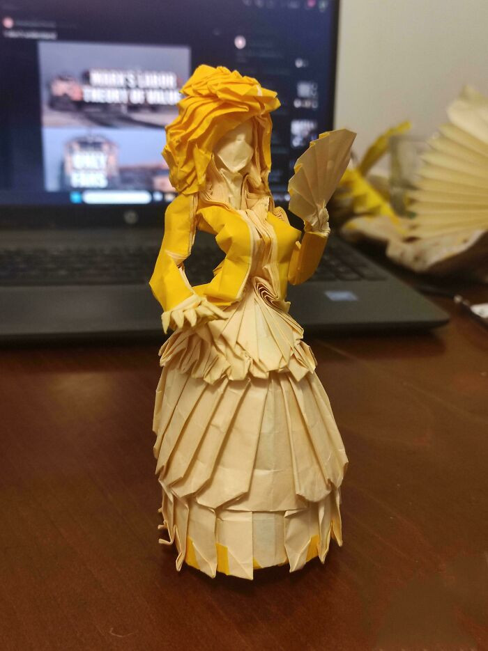 "An Origami Woman In Dress Folded From A Single Square Of Paper"