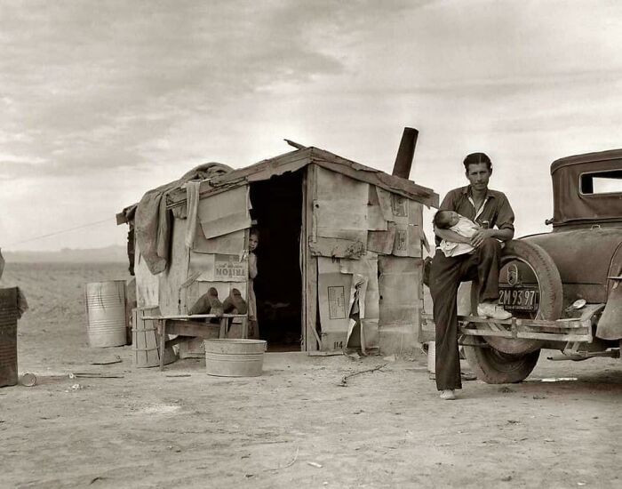 "A Migratory Mexican Field Worker Stands Beside His Makeshift Home Near A Pea Field In Imperial Valley, California, 1937"