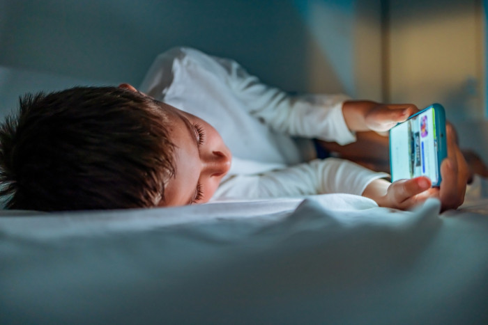 Child using a smartphone at home, highlighting early device ownership impacts