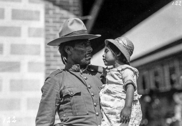 A Mexican federal soldier shares a final goodbye with his young daughter at a train station before leaving for war during the Mexican Revolution, 1915.