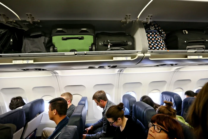 Traveler holding luggage with plastic wrap, highlighting unsafe travel security concerns