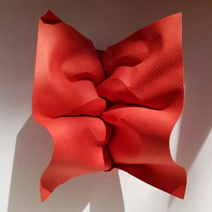 Folded paper “blow a kiss” sculpture, reciprocating folds inspired by natural motion.